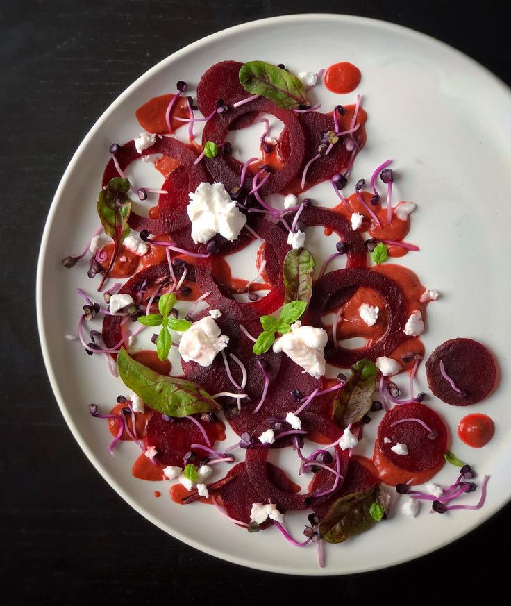 a white plate topped with beets and feta cheese on top of a table