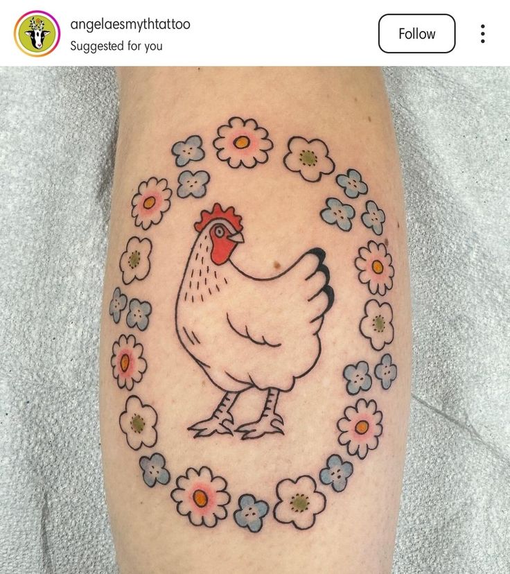 a chicken with flowers around it's neck on someones leg that is tattooed in the shape of a circle