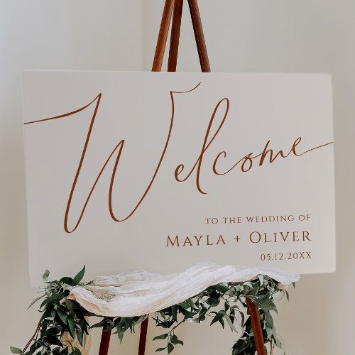 a welcome sign on a easel with greenery