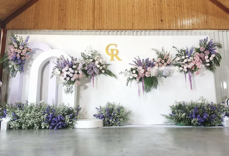 flowers and greenery are arranged on the wall in front of an arch at this wedding ceremony