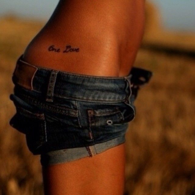 a woman's legs with the word love tattooed on her lower leg in front of a field