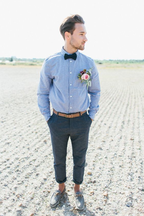 a man standing in the middle of a field wearing a bow tie and dress pants