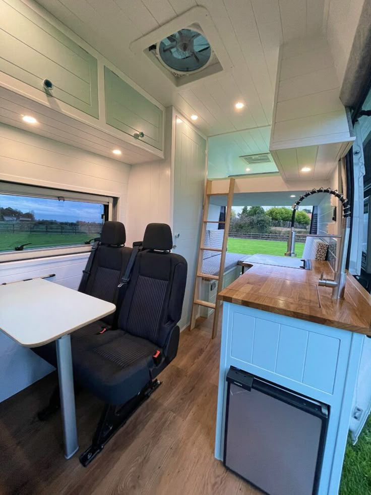 the inside of a camper with two chairs and a table in front of it