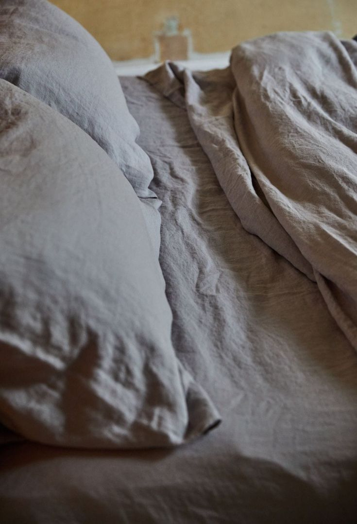 an unmade bed with two pillows on it