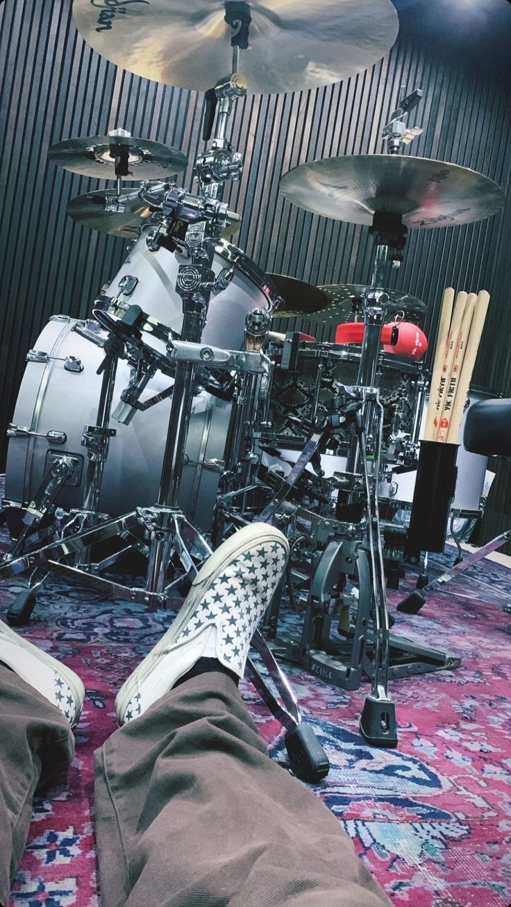 a person laying on the floor with their feet up in front of a drum set