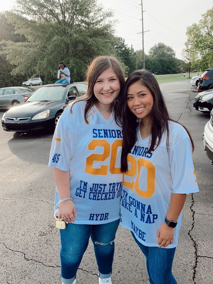 two young women standing next to each other in the parking lot wearing t - shirts