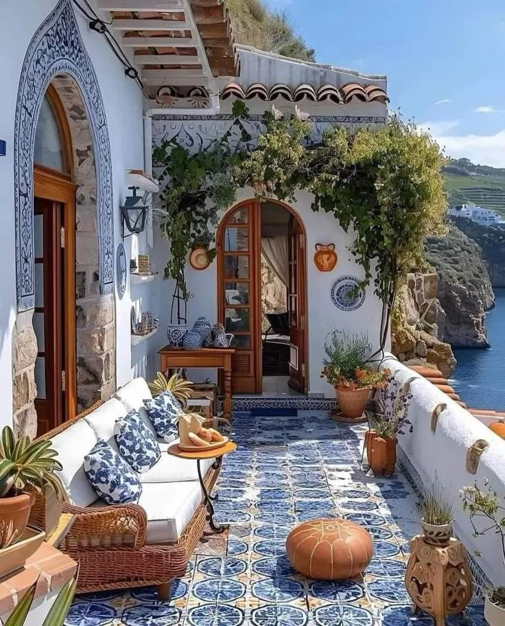 an outdoor patio with potted plants and blue tiles on the floor next to water