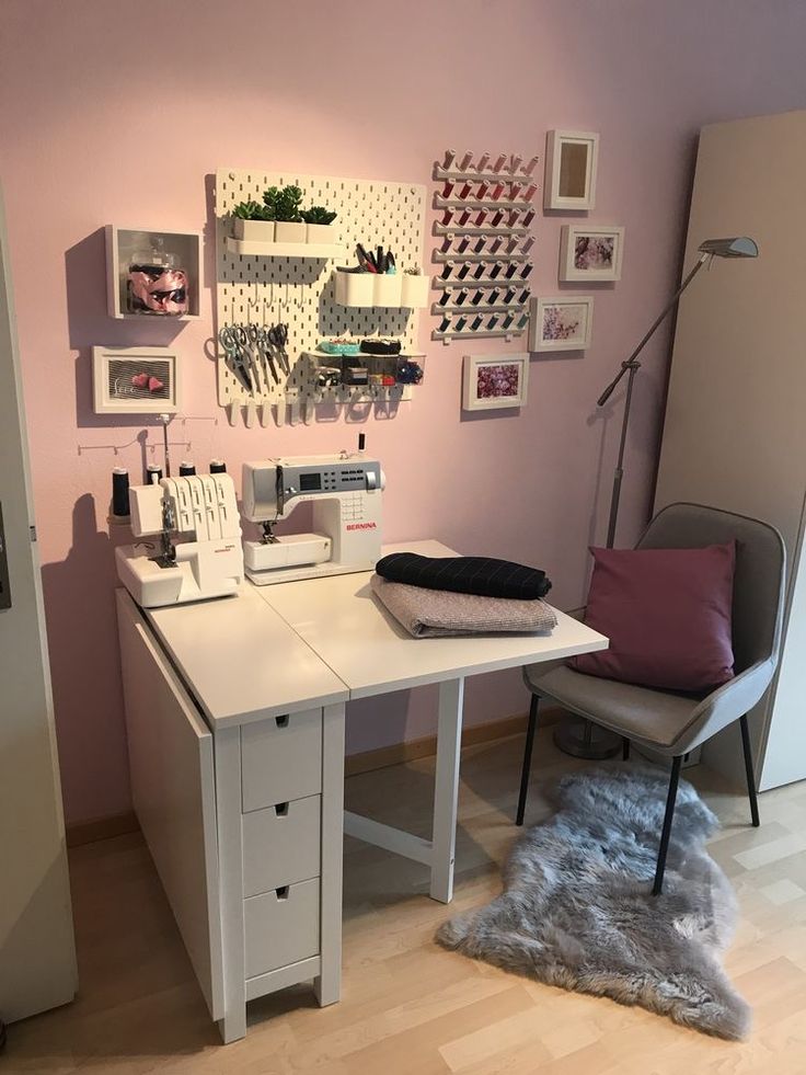 a sewing machine sitting on top of a white table next to a chair and shelf