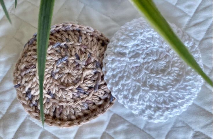 two crocheted baskets sitting next to each other on top of a white blanket