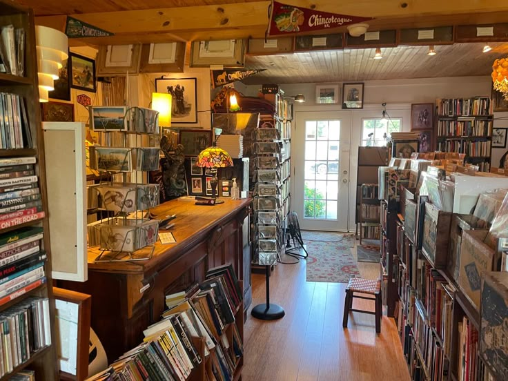 a room filled with lots of books next to a doorway covered in pictures and cds