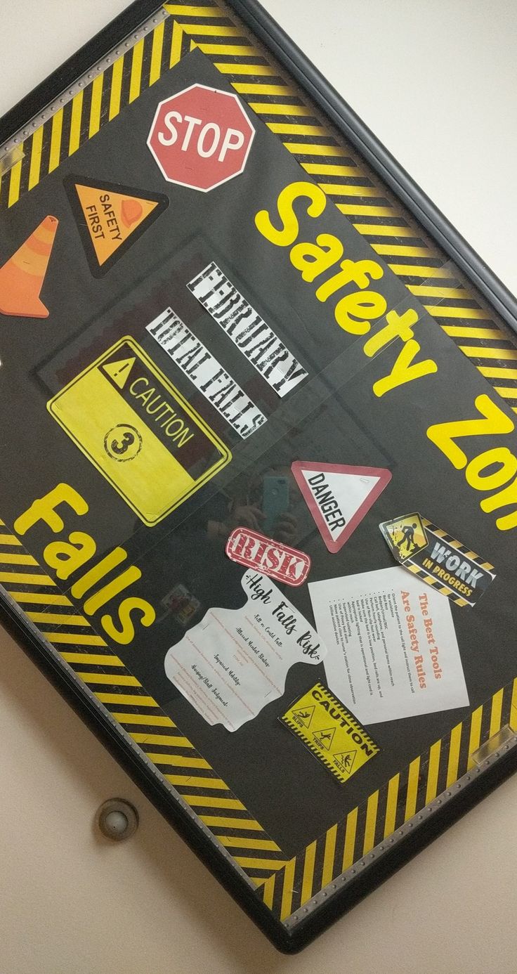 a black and yellow safety zone sign hanging from the side of a wall with stickers on it