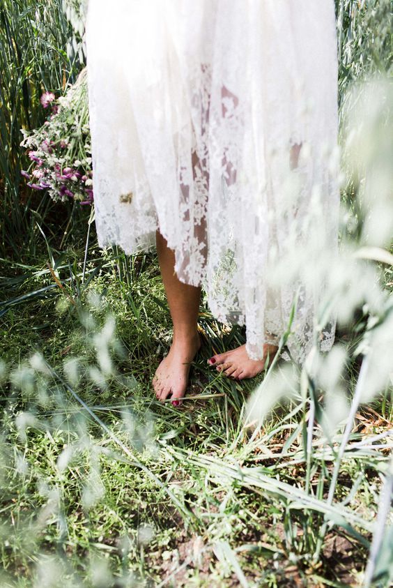 a woman standing in the grass with her feet up