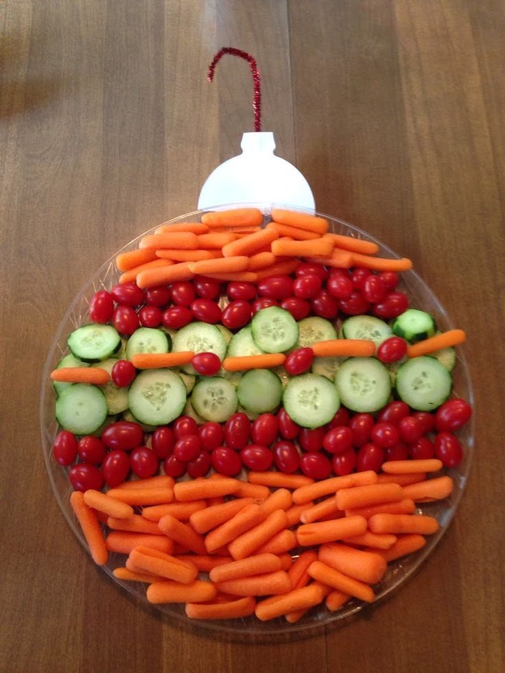 a platter with carrots, cucumbers and cherries arranged in the shape of a face