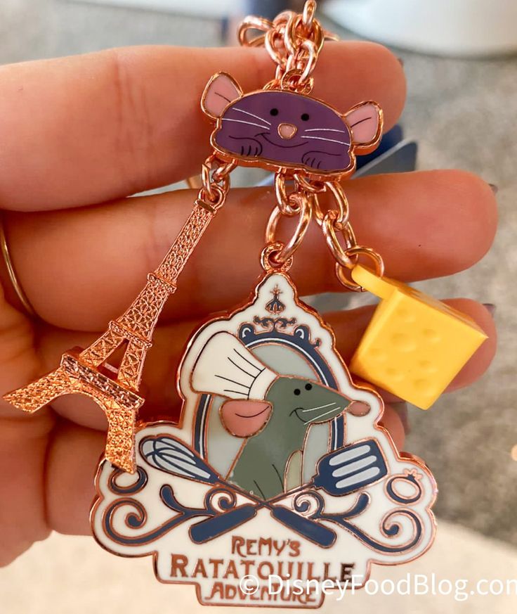 a person holding a keychain with a mouse and eiffel tower on it