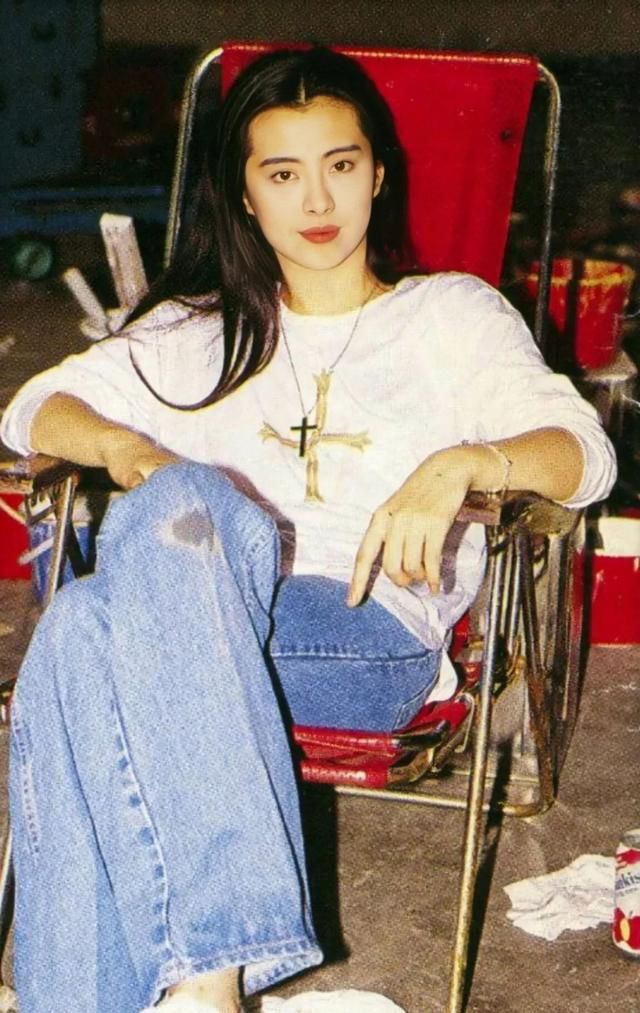 a woman sitting in a red chair with her legs crossed and looking at the camera