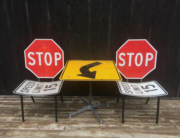 two stop signs are sitting next to each other on top of a table with another sign in front of them