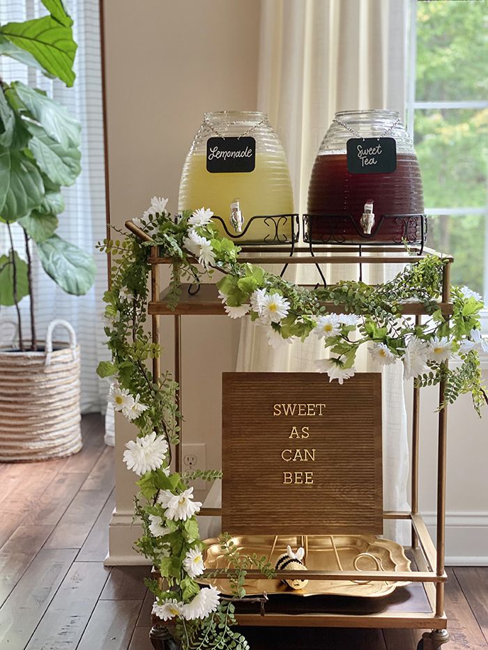 two drinks are sitting on top of a cart with flowers and greenery around it