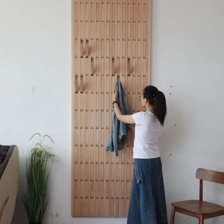 a woman standing in front of a wooden wall hanging on it's side holding onto a blue towel