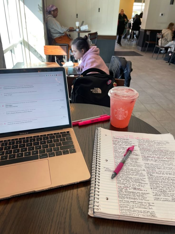 an open laptop computer sitting on top of a wooden table next to a cup of coffee