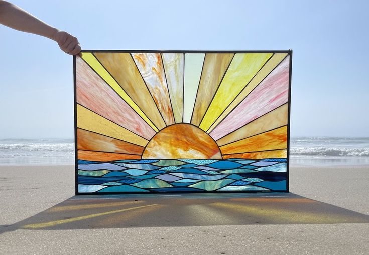 a stained glass window sitting on top of a sandy beach next to the ocean,