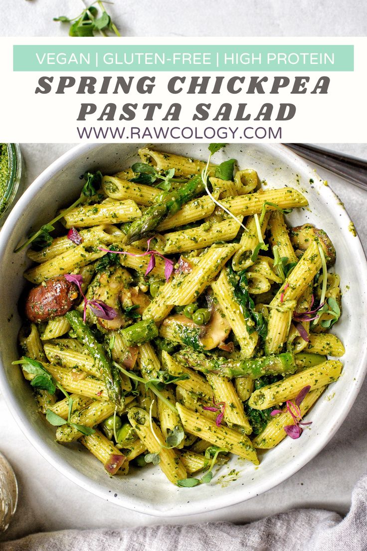 a white bowl filled with pasta and vegetables on top of a table next to a spoon