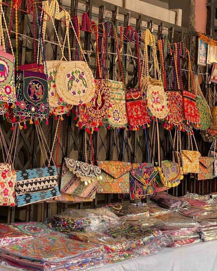 many bags and purses are on display for sale at an outdoor vendor's market