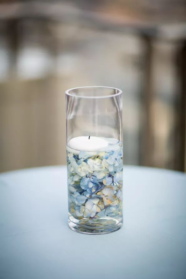 a glass filled with water and rocks on top of a table next to a candle