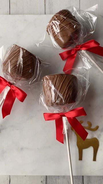 three chocolate lollipops wrapped in cellophane and tied with red ribbon