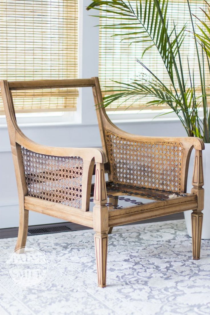 a wooden chair sitting on top of a rug next to a potted palm tree