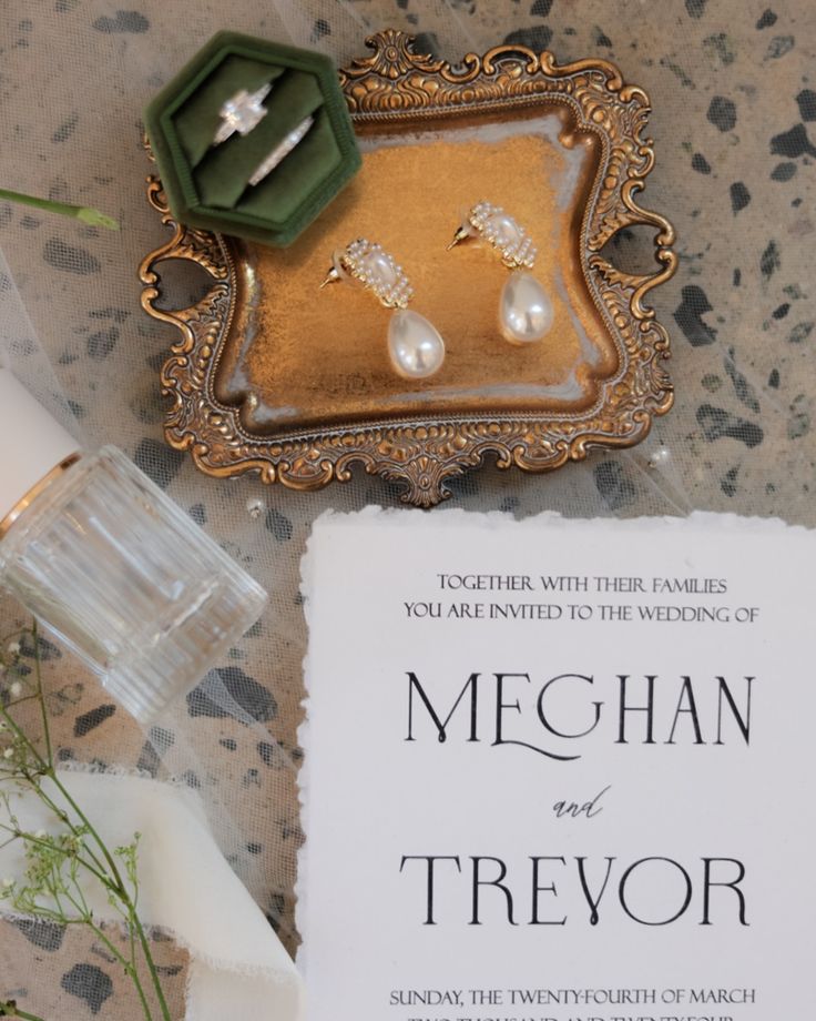 a wedding card and ring on top of a table