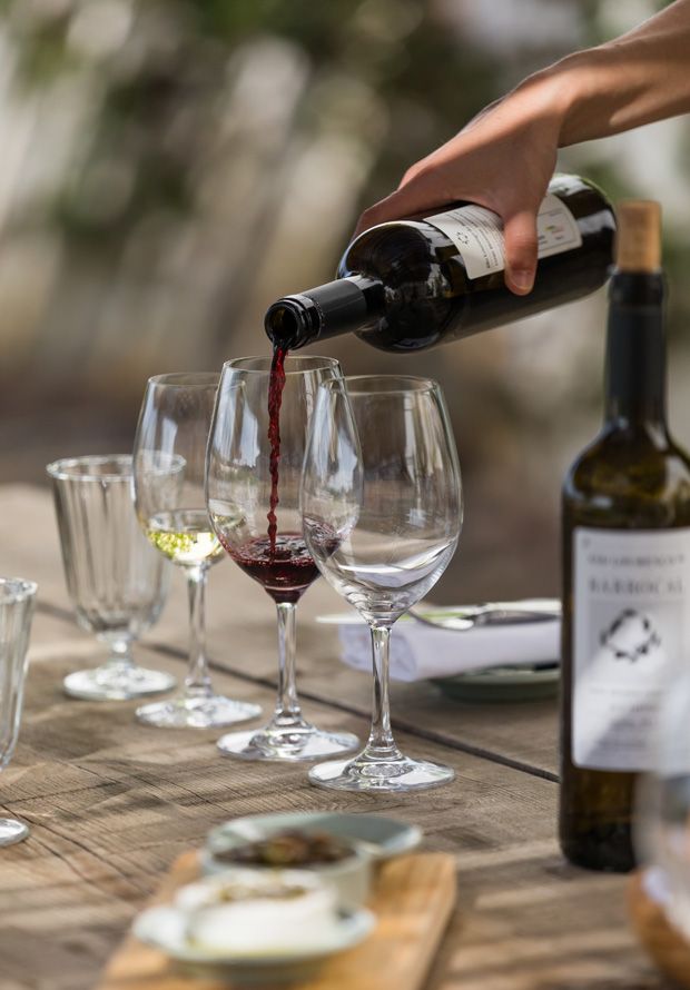 a person pouring wine into glasses on a table