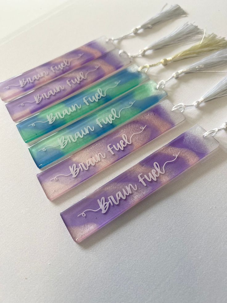 four glass bookmarks with writing on them and tassels hanging from the ends