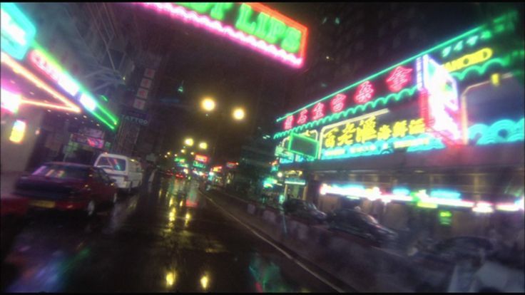 the city street is lit up with neon signs