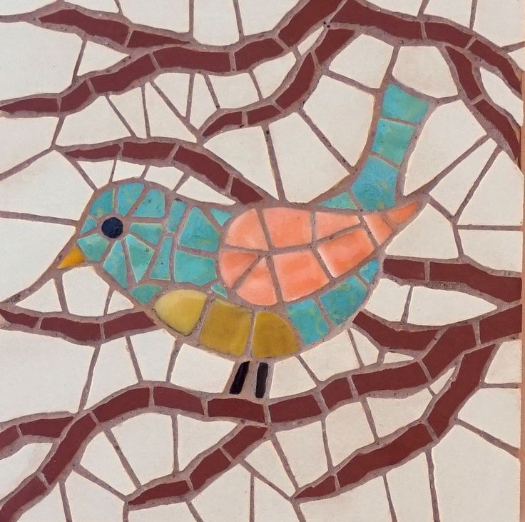 a colorful bird sitting on top of a tree branch covered in mosaic tiles and paint