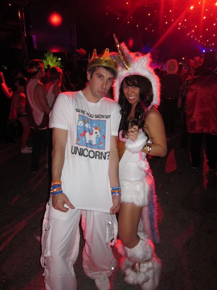 a man and woman dressed up as unicorns at a party with fireworks in the background