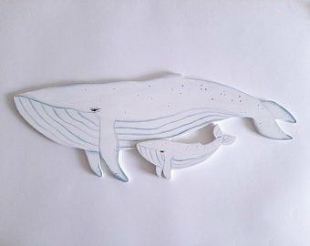 a ceramic whale is hanging on the wall in front of a white background with blue accents