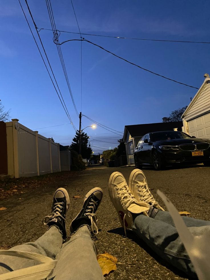 two people are sitting on the street with their feet propped up in front of them