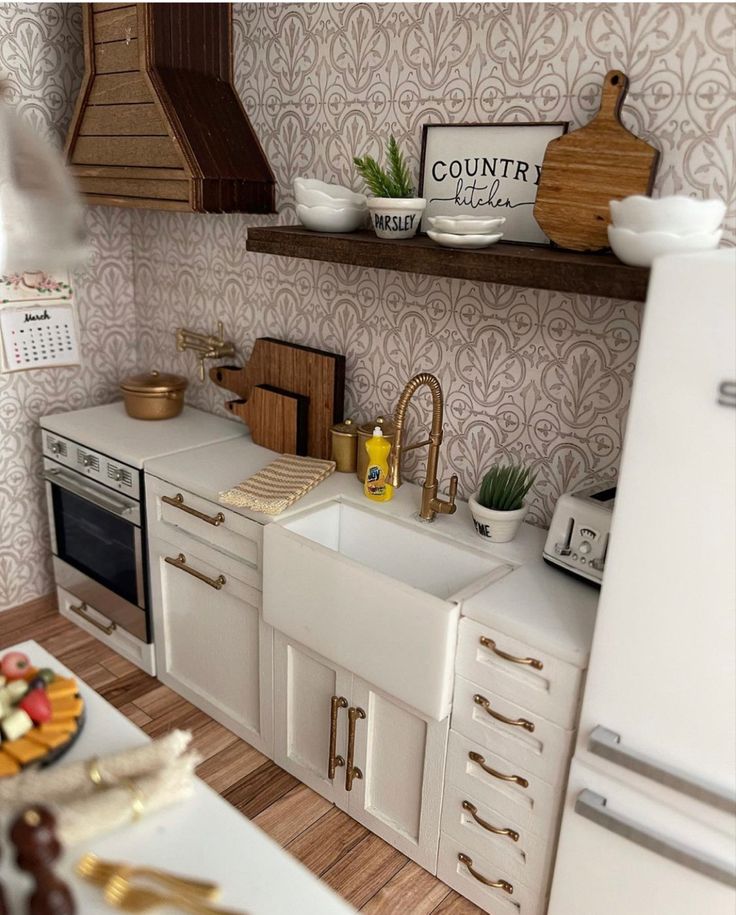 a model kitchen with white cabinets and gold handles