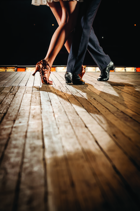 a man and woman dance on a wooden floor at the same time as they stand close to each other