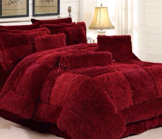 a bed with red comforters and pillows in a room