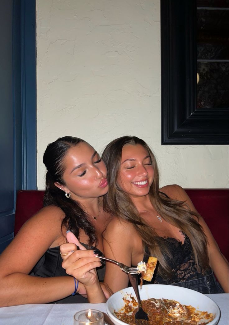 two beautiful young women sitting at a table eating food