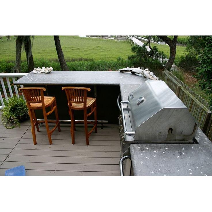 an outdoor grill with three chairs on it