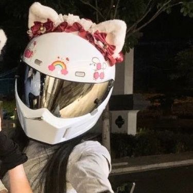 a woman wearing a hello kitty helmet on her motorcycle