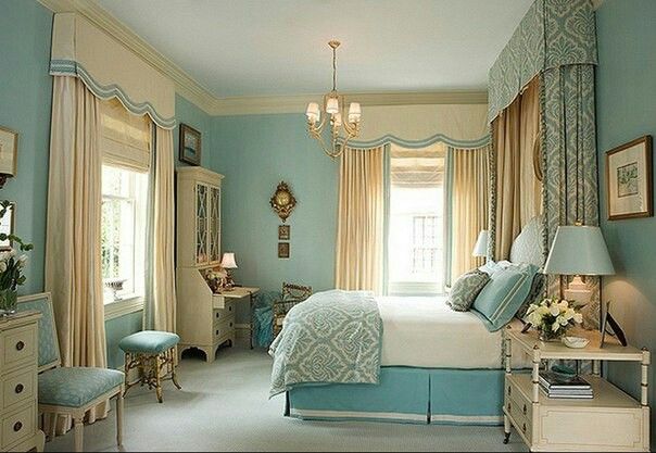 a bedroom with light blue walls and curtains on the window sill is decorated in white and gold