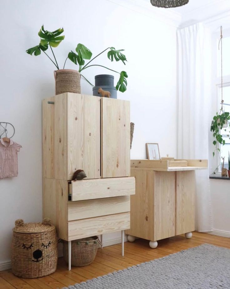 a wooden cabinet sitting next to a potted plant on top of a table in a room