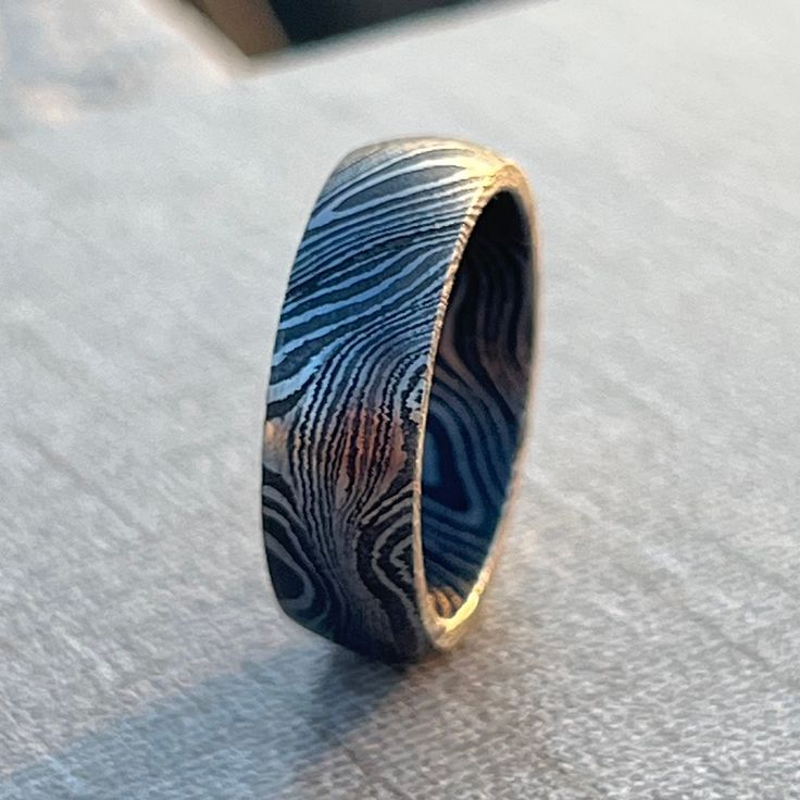 HANDMADE DAMASCUS STEEL RING WITH ACIDIC FINISH - DURABLE, UNIQUE, AND CUSTOM SIZED - ENGAGEMENT RING FOR HIM - DAMASCUS RING LOOKING FOR A PERFECT SUMMER GIFT OR A UNIQUE WEDDING BAND?   This handmade Damascus steel ring offers an elegant and durable design with a striking acidic finish. The ring combines a simple, yet aesthetic vibe, perfect for a custom wedding band or an everyday alternative ring. The smooth interior of the Damascus steel adds comfort while maintaining its timeless appeal. - Aesthetic Band, Alternative Ring, Engagement Ring For Him, Damascus Ring, Damascus Steel Ring, Perfect Gift For Boyfriend, Custom Wedding Band, Elegant Pattern, Unique Wedding Bands