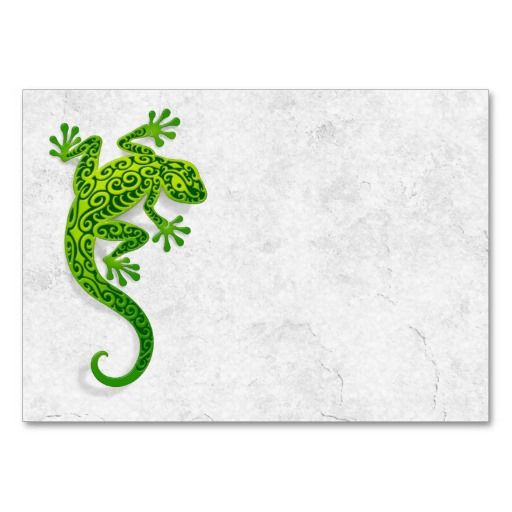 a green lizard sitting on top of a white wall