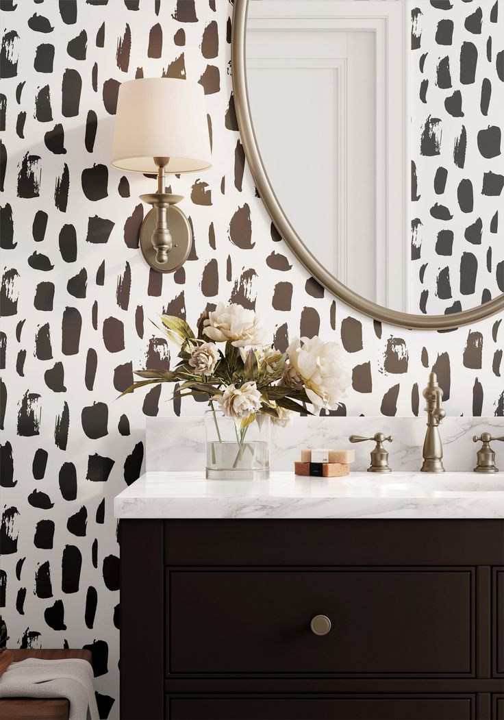 a bathroom vanity with a mirror and black and white wallpaper on the wall behind it