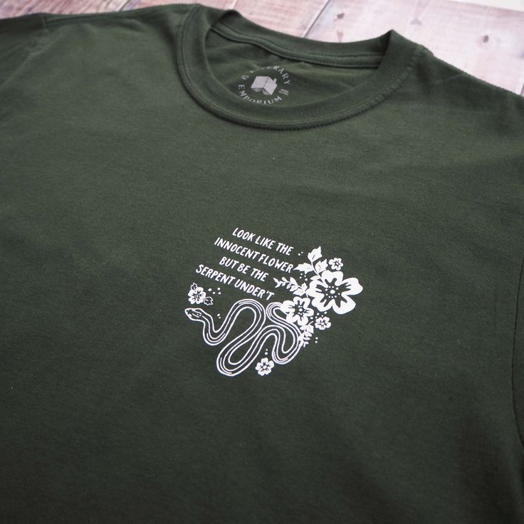 "A loose fit unisex t-shirt screen printed with a quote from Lady Macbeth in Shakespeare's famous tragedy. The perfect literature themed slogan t-shirt. \"Look like the innocent flower, But be the serpent under 't.\" - Act I Scene V This design has been screen printed in the South West of England, onto a soft, forest green t-shirt which is made from 100% cotton. The relaxed fit top is a comfy, yet stylish item of clothing and makes a great gift for a book lover. Made from: 100% cotton. Machine w Look Like The Innocent Flower, Green Serpent, Shakespeare Gifts, Feminist Tshirt, Literature Gifts, Lady Macbeth, Screen Printed Tshirts, The Serpent, Slogan T Shirt