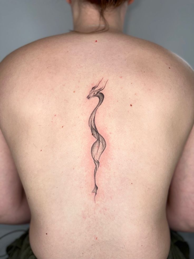 a woman's back with a snake tattoo on it